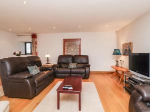 sala de estar con muebles de cuero y TV de pantalla plana en Bride Cross Granary, en Otley