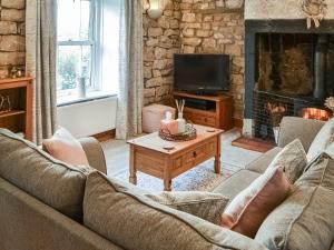 a living room with a couch and a fireplace at Middles Cottage in West Woodburn