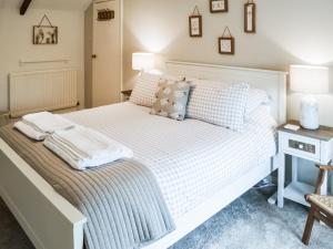 1 dormitorio con cama blanca y mesita de noche con mesa en Middles Cottage, en West Woodburn
