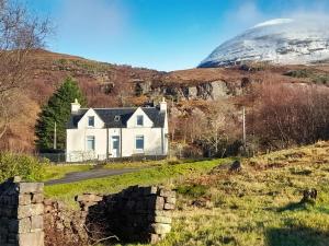 a house on a hill with a mountain in the background at Sunnybank Cottage in Inveralligin