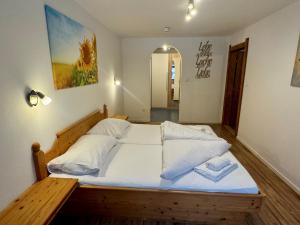 Schlafzimmer mit einem Holzbett mit weißer Bettwäsche und Kissen in der Unterkunft Urlaub mit Hund im Familienparadies MoNi, FeWo 15 in Thiersee