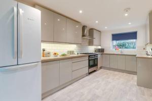 a kitchen with white cabinets and a refrigerator at Tiger House Stevenage 5 Bed 4 Bath Group Bookings in Stevenage