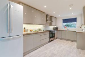 スティーブニッジにあるTiger House Stevenage 5 Bed 4 Bath Group Bookingsのキッチン(白いキャビネット、冷蔵庫付)