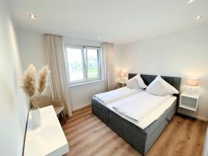 um quarto com uma cama grande e uma janela em Seeliebe Apartments Schwerin - am See, Seeblick, PKW, Sauna, XXL-Balkon, Terrasse, modern em Schwerin