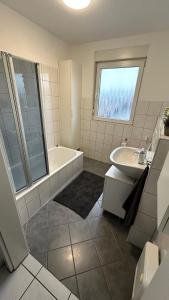 La salle de bains blanche est pourvue d'une baignoire et d'un lavabo. dans l'établissement 140 qm Maisonette-Whg ruhig und doch zentral, à Florstadt