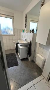 La salle de bains blanche est pourvue d'un lavabo et d'un miroir. dans l'établissement 140 qm Maisonette-Whg ruhig und doch zentral, à Florstadt