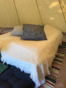 a bed in a tent with a pillow on it at Hommen Gård Glamping in Risør