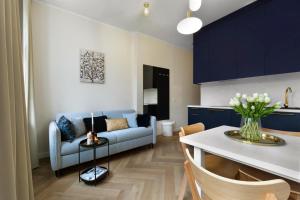 een woonkamer met een blauwe bank en een tafel bij Elite Apartments Grobla Center in Gdańsk