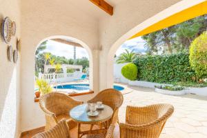 une terrasse avec une table, des chaises et une piscine dans l'établissement Villa Carlota Moraira, à Moraira