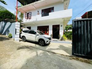 a white car parked in front of a house at Ambuluwawa View Inn in Gampola