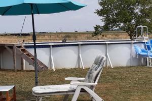 una silla y una sombrilla junto a un edificio en A la campagne chez l'habitant, en Germainville