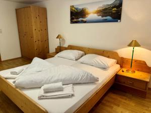 Una cama grande con sábanas blancas y toallas. en Familienparadies MoNi Ferienwohnung 17, en Thiersee