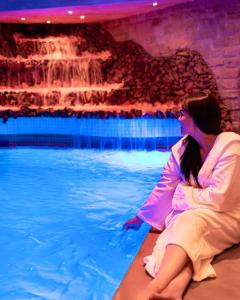 Eine Frau, die vor einem Pool sitzt. in der Unterkunft Art Palace Suites & Spa in Casablanca