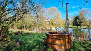 un barril de madera en la hierba junto a un lago en Exclusive Coach House with Lakeside Hot Tub on Country Estate, en Toddington