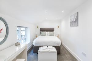 a white bedroom with a bed and two windows at Livestay Stunning 2 bed apartments in Stratford in London