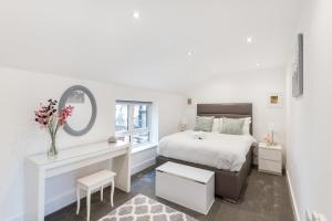 a bedroom with a bed and a desk and a mirror at Livestay Stunning 2 bed apartments in Stratford in London