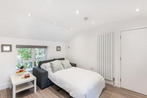 a white bedroom with a bed and a window at Livestay Stunning 2 bed apartments in Stratford in London