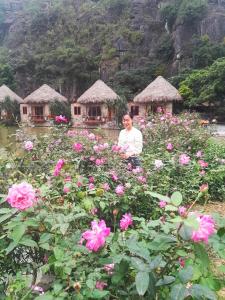 a woman in a field of flowers with huts in the background at Hang Mua Eco Garden in Xuân Sơn