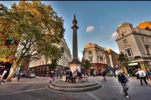 un grupo de personas sentadas alrededor de un monumento en una calle en Central London Gem 1 BR Flat Piccadilly Circus VR8, en Londres