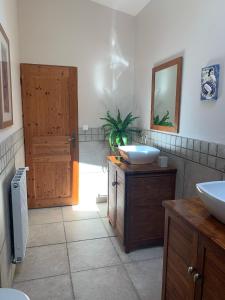 een badkamer met 2 wastafels en een houten deur bij Les Guittieres Gites in Sarcé