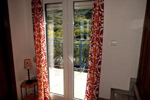 2 puertas de cristal con cortinas rojas y blancas en una habitación en Ocean Vista Retreat, en Skála