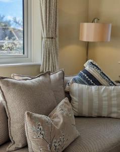 a bunch of pillows sitting on a couch with a window at Firs End - Close to Norfolk Broads and Coast - Crabpot Cottages Sheringham in North Walsham