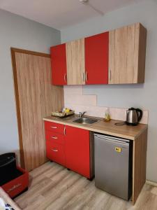 a small kitchen with red cabinets and a sink at Студио Релакс, Ахелой in Aheloy