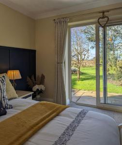 a bedroom with a bed and a large window at Firs End - Close to Norfolk Broads and Coast - Crabpot Cottages Sheringham in North Walsham