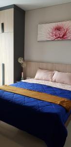 a bedroom with a blue bed with a painting on the wall at One Residence #11AI in Batam Center