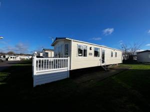 a white mobile home with a white fence at Lovely Caravan With Decking At Cherry Tree Holiday Park In Norfolk Ref 70528c in Great Yarmouth