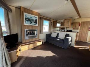 een woonkamer met een bank en een tv bij Lovely Caravan With Decking At Cherry Tree Holiday Park In Norfolk Ref 70528c in Great Yarmouth