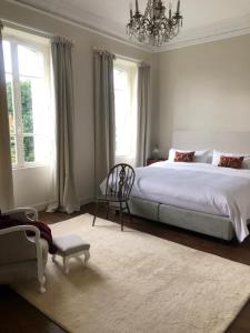 a bedroom with a bed and a chair and a chandelier at La Pommeraie Champsecret, Lower Normandy in Champsecret
