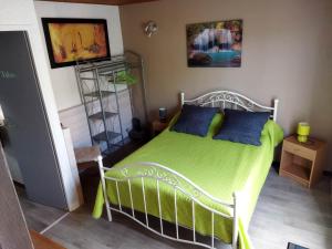 a bedroom with a green bed with blue pillows at Agréable villa 100 m de la plage in Poggio-Mezzana