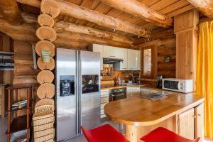 a kitchen with a refrigerator and a wooden ceiling at Chalet l'Epicurien - Au calme avec grand jardin in Saint-Martin-du-Puy