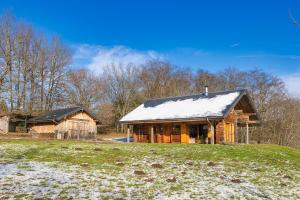 une cabane en rondins avec un toit recouvert de neige dans l'établissement Chalet l'Epicurien - Au calme avec grand jardin, à Saint-Martin-du-Puy