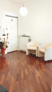 a living room with two white chairs and a wooden floor at House Rossini in Turin