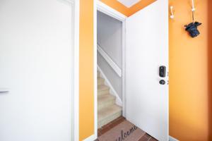a hallway with orange walls and a white door with stairs at Retro Loft steps from Duke in Durham