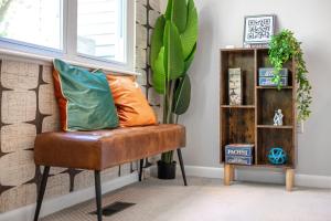 a room with a brown chair with an orange pillow at Retro Loft steps from Duke in Durham +45 photos