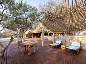 a deck with chairs and a table and a hut at Evolve Back Kalahari in Central Kalahari