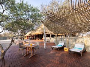 una terrazza con sedie, tavolo e capanna di Evolve Back Kalahari a Central Kalahari