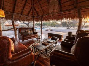 a living room with leather couches and a table at Evolve Back Kalahari in Central Kalahari