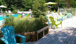 una terraza con sillas, una mesa y una piscina en Camping USHUAÏA Villages Au Bois Joli en Andryes