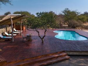 a deck with a swimming pool and a table and chairs at Evolve Back Kalahari in Central Kalahari
