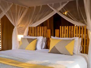 a bedroom with a canopy bed with yellow and white pillows at Evolve Back Kalahari in Central Kalahari