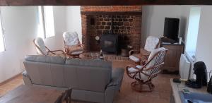 ein Wohnzimmer mit einem Sofa, Stühlen und einem Kamin in der Unterkunft Cottage de Vittefleur in Vittefleur