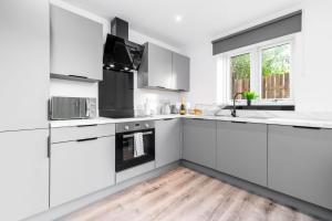 a white kitchen with white cabinets and a wooden floor at New Luxe 2 Bedroom Apartment - Private Parking - Balcony - 2MC in Birmingham