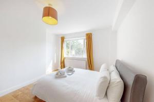 Cette chambre comprend un lit avec des oreillers blancs et une fenêtre. dans l'établissement Cozy 3 bedroom apartment in Brixton, à Londres