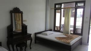 a bedroom with a bed and a mirror and a window at Raditia Homestay in Ubud
