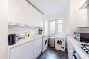 una cocina blanca con lavadora y secadora. en Cozy 3 bedroom apartment in Brixton, en Londres