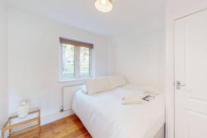 a white bedroom with a white bed and a window at Cozy 3 bedroom apartment in Brixton in London